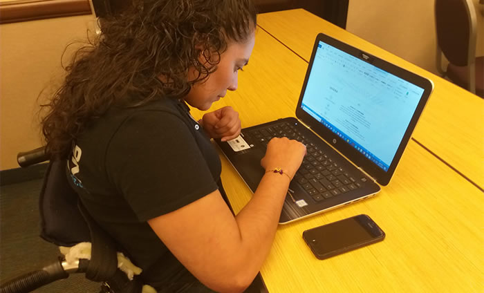 Sandra con discapacidad motriz trabajando en su laptop.